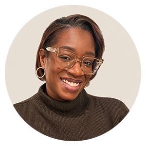 Smiling woman with glasses wearing a brown turtleneck sweater