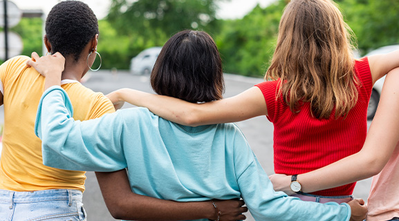 Three women standing together, showing support and connection in a community setting.